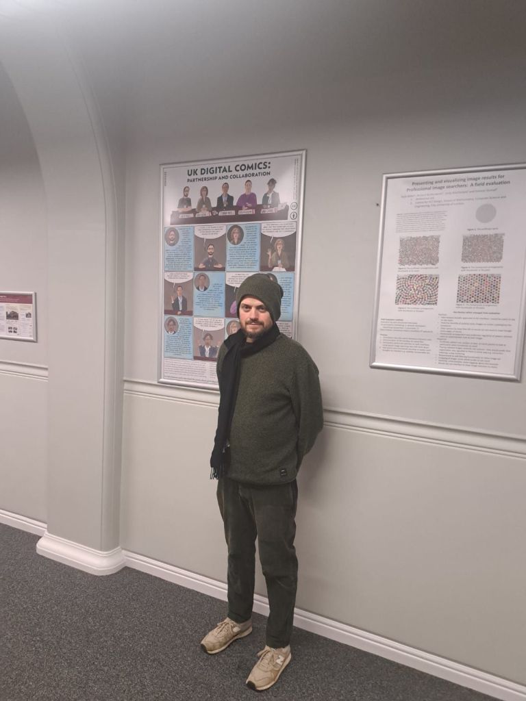 Francisco de la Mora with his framed comics poster behind him. 