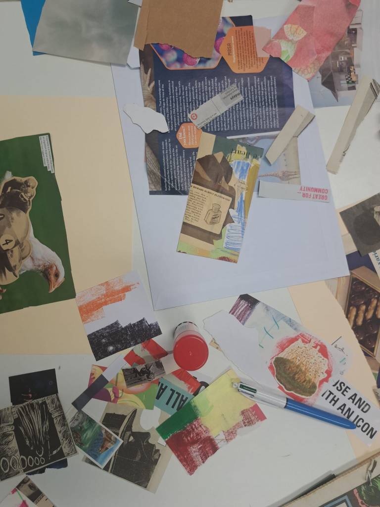 Student collage work in process on desk, paper, clippings, glue stick